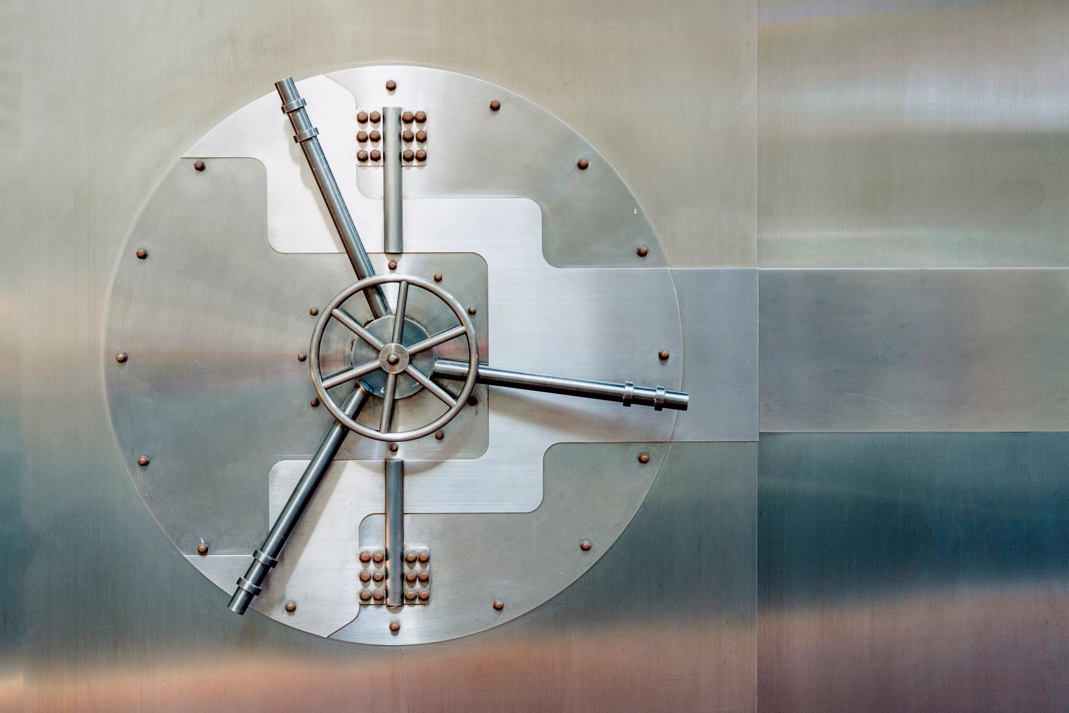 Close-up of a large round vault door with locking mechanism secured on metal wall